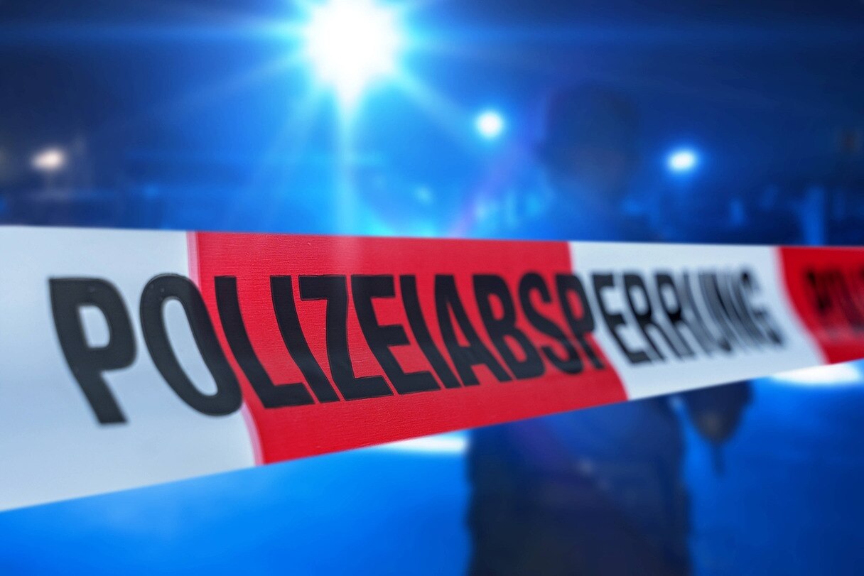 Absperrband vor einem Polizeieinsatz mit Blaulicht. 