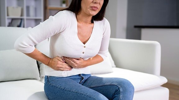 Eine Frau hält sich die schmerzende rechte Seite des Bauches