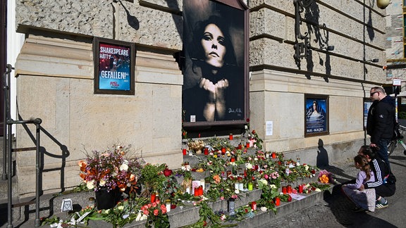 Blumen wurden auf Stufen vor einem Foto niedergelegt.