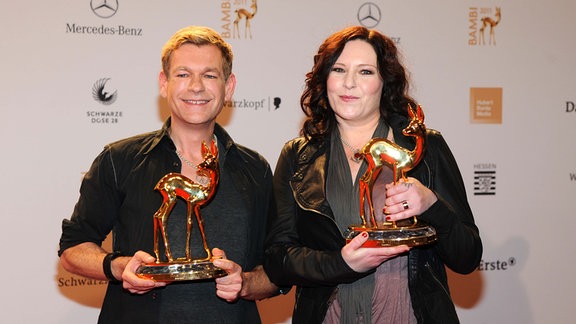 Anna R Rosenstolz und Peter Plate halten zwei Bambi-Preise in den Händen.