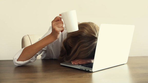 Müde Frau mit Laptop sitzen am Schreibtisch