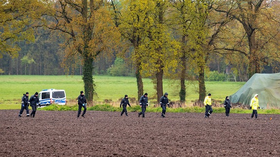 Polizisten gehen auf der Suche nach einem vermissten Jungen über ein Feld