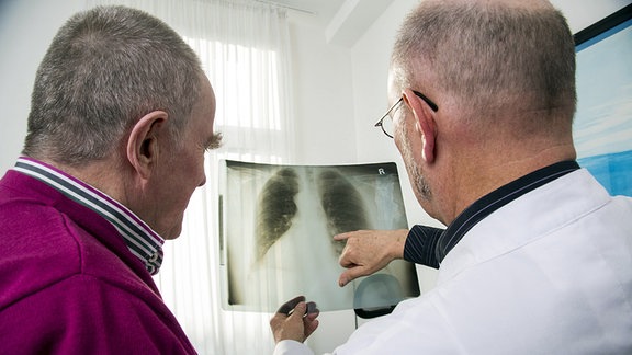 Ein Arzt bespricht mit einem Patienten ein Röntgenbild.