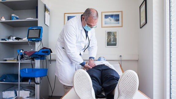 Ein Arzt untersucht einen Patienten auf einer Liege