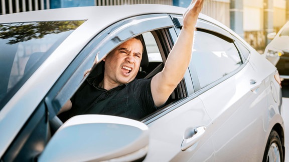 Autofahrer schreit aus dem Seitenfenster.