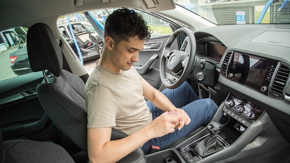Blick in den Fahrzeug-Innenraum: ein Mann hinter dem Steuer