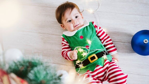 Ein Baby liegt am Weihnachtsbaum.