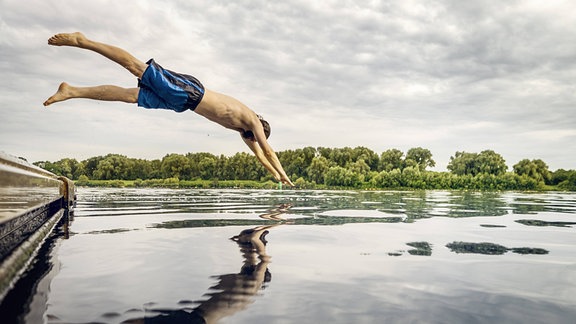 Ein Mann macht einen Kopfsprung ins Wasser.