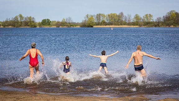 Eine Familie läuft bei sonnigem Wetter in den Hufeisensee in der Region Hannover