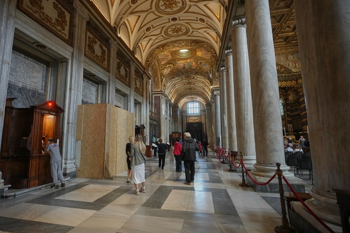 Menschen gehen in der Basilika Santa Maria Maggiore, wo Papst Franziskus am 26. April beigesetzt wird, an einem mit Holzplatten abgesperrten Bereich vorbei.