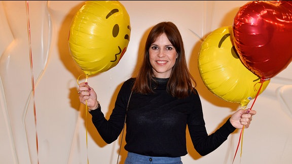 Schauspielerin Birthe Wolter hält Luftballons und lächelt in die Kamera.