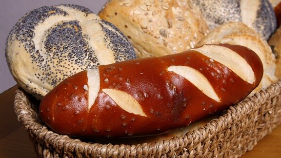 Brötchen und eine Laugenstange liegen in einem Korb.