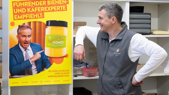 Rico Heinzig, Imker, steht neben einem Plakat mit dem Foto des Moderators Jan Böhmermann.