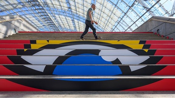Stephan von Wolffersdorff beklebt für ZWA Design in der Glashalle der Messe Leipzig die 36 Stufen einer Treppe mit dem Logo der Buchmesse.