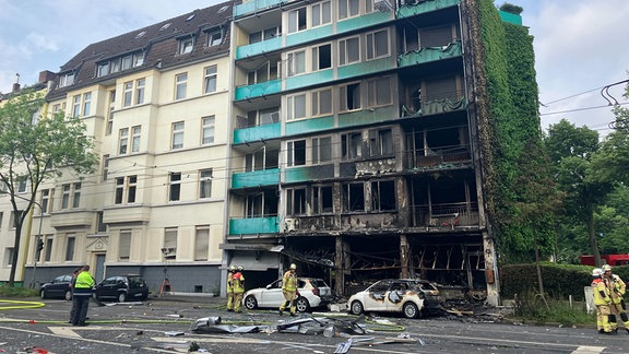 Trümmer liegen auf einer Straße in Düsseldorf vor einem Haus, in dem ein Brand wütete. 