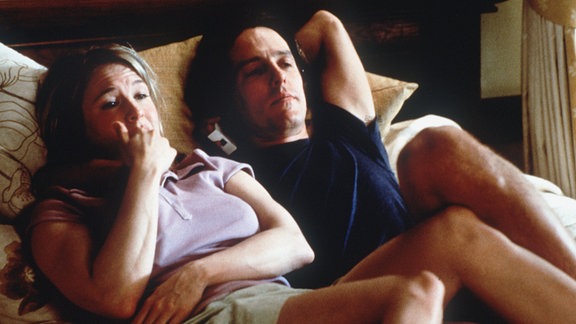 Die junge Bridget Jones (Renee Zellweger) liegt in dem neuen Kinofilm "Bridget Jones - Schokolade zum Frühstück" mit ihrem Freund und Chef Daniel Cleaver (Hugh Grant) auf dem Bett (Szenenfoto)