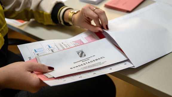 Eine Verwaltungsmitarbeiterin steckt Unterlagen für die Neuwahl zum 21. Deutschen Bundestag in einen Umschlag (gestellte Szene).