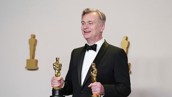 Christopher Nolan posiert im Presseraum mit den Preisen für die beste Regie und den besten Film für "Oppenheimer" bei der Oscar-Verleihung.