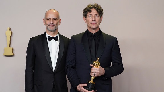 James Wilson (l) und Jonathan Glazer posieren mit dem Preis für den besten internationalen Spielfilm für "The Zone of Interest" aus dem Vereinigten Königreich
