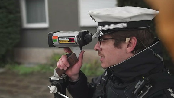 ein Polizist mit einem Geschwindigkeitsmesser
