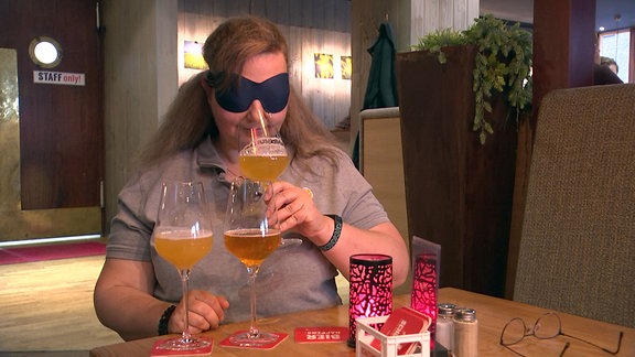 Eine Frau bei einer Bierverkostung mit verbundenen Augen.