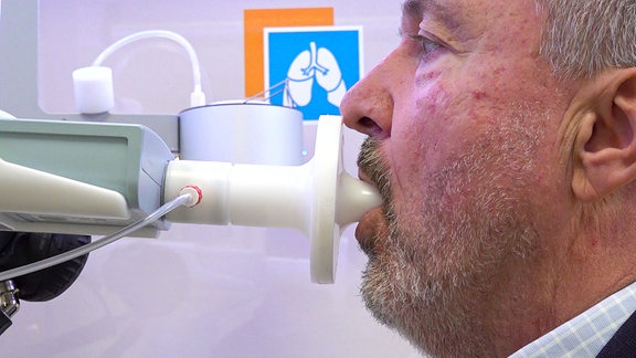 Ein Mann pustet in ein Atem-Messgerät
