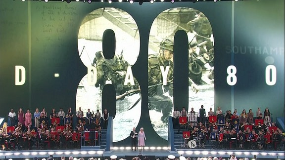 König Charles und Camilla kommen zur Gedenkfeier an den D-Day vor 80nJahren im britischen Portsmouth auf die Bühne