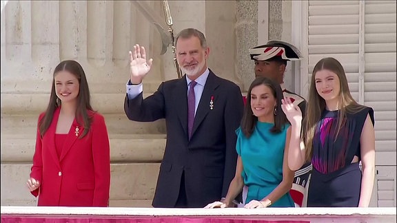 Die spanische Königsfamilie winkt von einem Balkon aus.