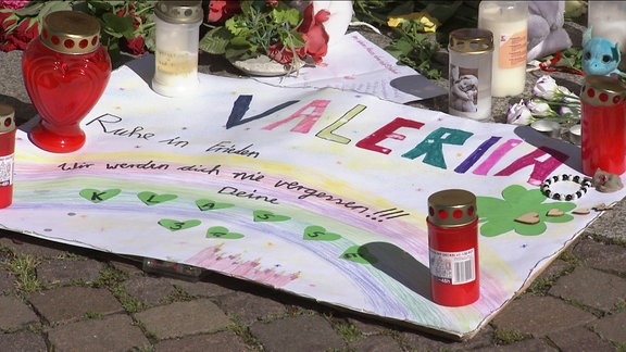 Auf einem bunten, mit Kerzen beschwerten Plakat steht "Valeria".