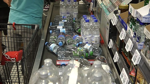 Eine Menge Wasserflaschen liegen auf einem Band einer Supermarktkasse.