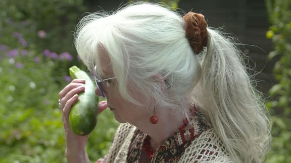 Frau riecht an Zucchini