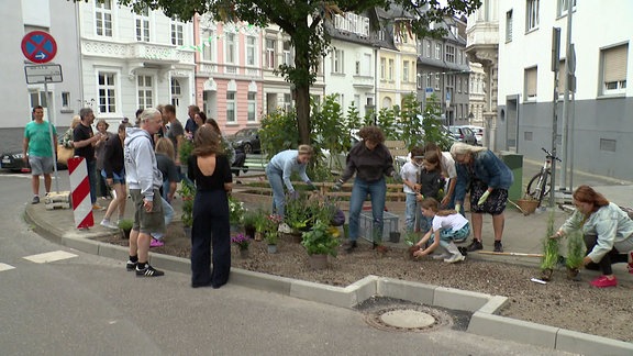 Familien begrünen eine Straßenecke.