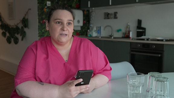 Eine Frau hält ein Smartphone in der Hand.