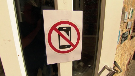 Ein Smartphone-Verbotsschild hängt an einer Tür.