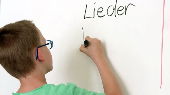 Ein Junge schreibt an einer Wandtafel