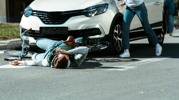 Radfahrer wurde von Auto angefahren, Fahrerin eilt zur Hilfe.