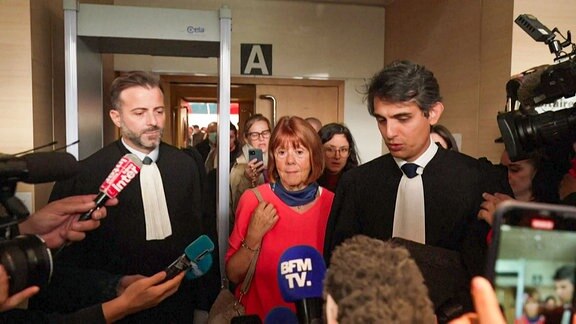 Eine Frau mit ihren Anwälten spricht vor der Presse