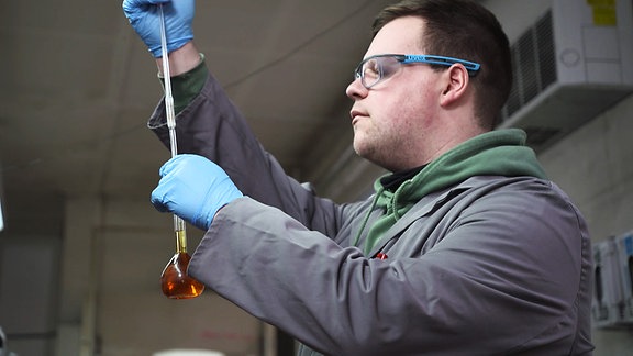 Ein Mann überprüft eine Flüssigkeit in einem Glasbehälter.