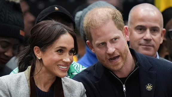 Harry und Meghan unterhalten sich bei einer öffentlichen Veranstaltung.