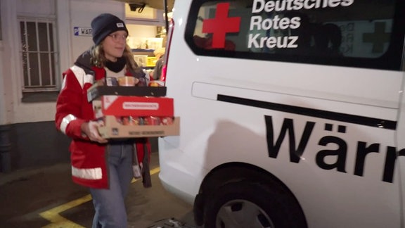 Eine Frau packt Lebensmittel in einen Bus.