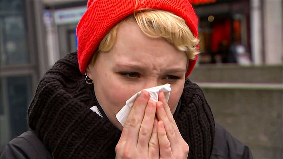 Eine Frau niest in ein Taschentuch