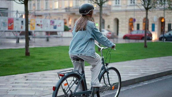 Eine Frau mit Helm fährt auf einem Fahrrad