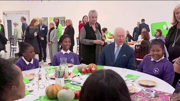 König Charles an einem Tisch bei einer Hilfsorganisation