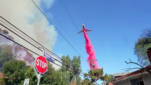 Löschflugzeug am Himmel über einer städtischen Straße