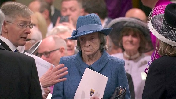 Maggie Smith in einem blauen Kostüm in einer Menschenmenge