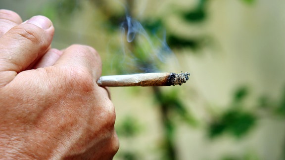 Männerhand mit rauchendem Joint