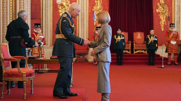 Anna Wintour (r), Chefredakteurin der Vogue, schüttelt im Buckingham Palace König Charles III. die Hand.