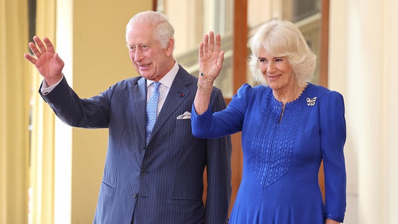 König Charles III. und Königin Camilla winken und lächeln.