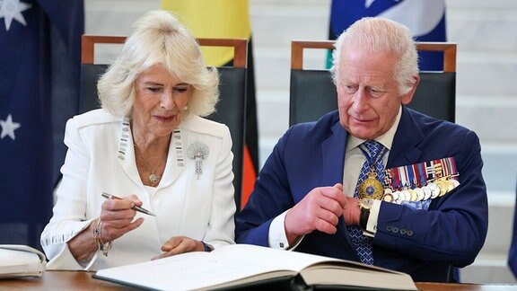 König Charles und Königin Kamilla unterzeichnen in einem Buch