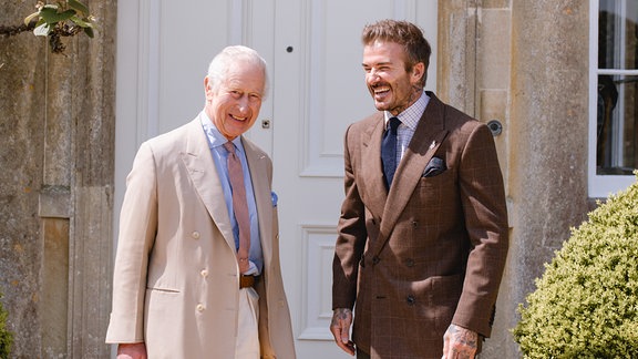 König Charles III. und David Beckham lachen gemeinsam